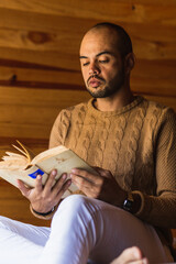 hombre pelón con barba leyendo un libro con un suéter para el frio