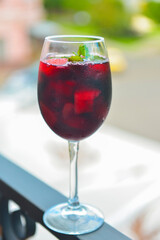 Red wine glass outside. Selective focus on glass, blurred background. Fruit alcohol drink for hot summer weather.