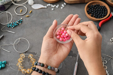 Female jewelry designer with beads at table