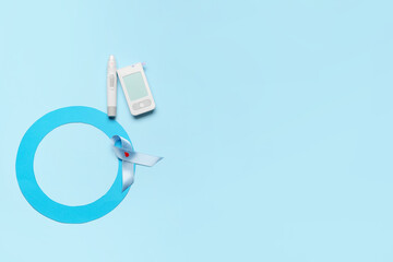 Glucometer with lancet pen, blue ring and awareness ribbon on color background. Diabetes concept