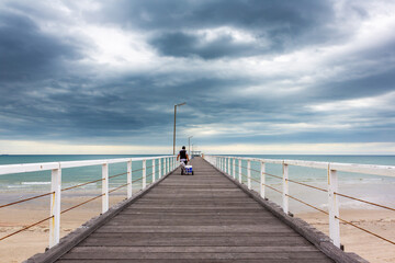 A man walking out with fishing gear on the old largs bay jetty in adelaide south australia on october 26th 2020