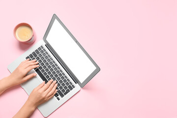 Female hands with modern laptop and cup of coffee on color background