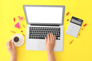 Female hands with modern laptop and cup of coffee on color background