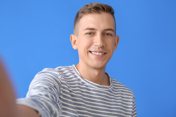 Obraz premium Young man taking selfie on color background