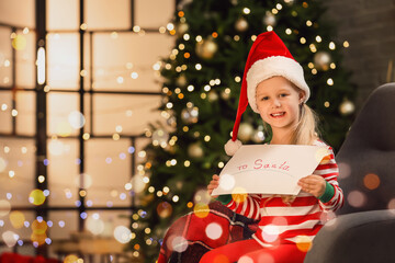 Obraz na płótnie Canvas Cute little girl with letter to Santa at home