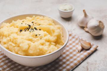 Bowl with tasty mashed potato and garlic on table
