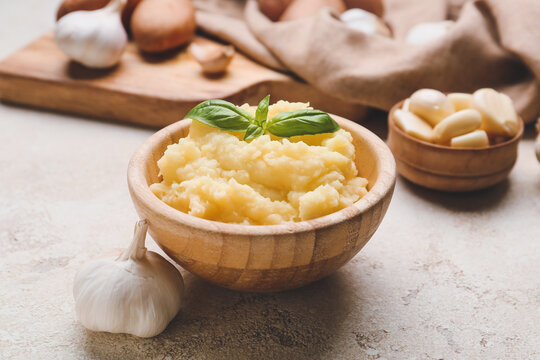 Bowl with tasty mashed potato and garlic on table