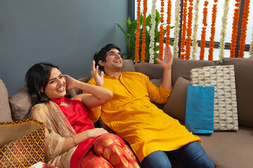 Young couple talking to each other while laying down on sofa 	