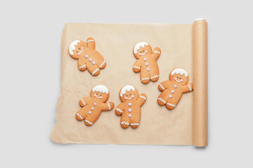 Parchment with tasty gingerbread cookies on light background