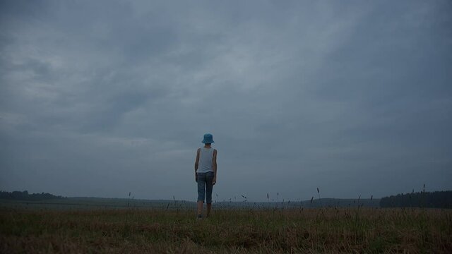 boy walks on a field in rainy weather in the evening