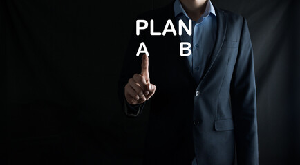 Businessman in a suit chooses options for plan development, Plan A, Plan B. on virtual screen. Business strategy, choosing a plan or decision concept.