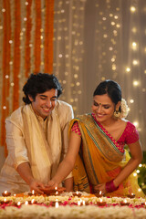 Couple sharing happiness of lighting diyas together for Diwali	