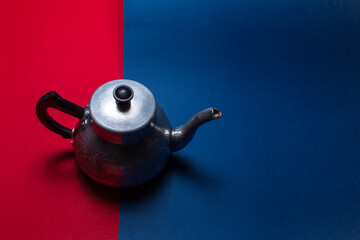 Obraz na płótnie Canvas Top view of vintage aluminum teapot, on two dark backgrounds of red and blue colors with copy space.