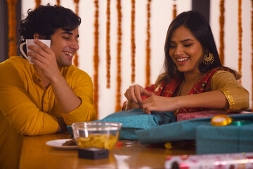Young couple spending time while packing Diwali gifts	