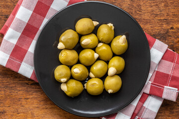 Pitted green olives stuffed with almonds on plate.