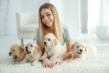 Cute young woman kisses and hugs a Labrador Retriever puppy dog. Love between owner and dog. In the room at home, interior. High quality photo.
