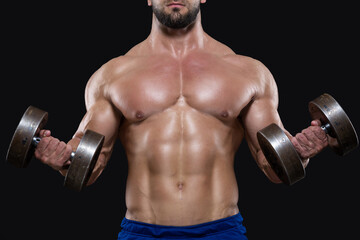 Fototapeta na wymiar Close up of muscular sportsman lifting heavy dumbbells showing his strong biceps isolated on black backgrounds