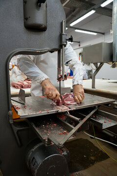 Butcher cuts freshly slaughtered meat of pork for sale and further processing as sausage