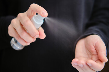 Woman wipes her hands with an alcohol-based sanitizer spray. virus. covid
