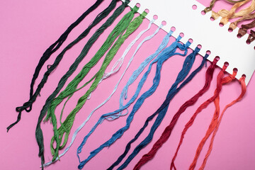 Multicolored threads for embroidery floss on a pink background