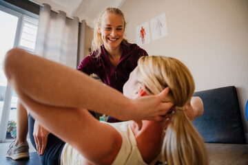 Female patient correcting crunch techniques with physio therapist in exercise studio - Powered by Adobe