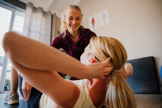 Female patient correcting crunch techniques with physio therapist in exercise studio