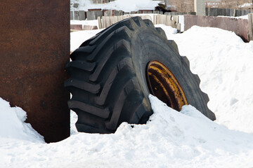 Car tire, car wheel covered with snow next to brown building, large amount of snow, copy space, close-up - Powered by Adobe