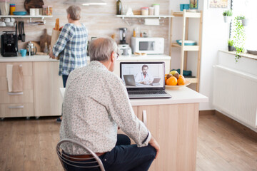 Senior couple having a video conference with doctor talking ill treatment. Online health consultation for elderly people drugs ilness advice on symptoms, physician telemedicine webcam. Medical care