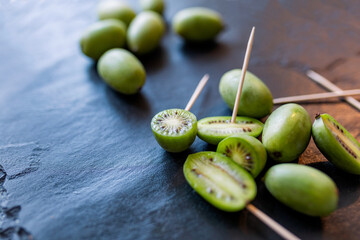 New Zealand exotic food. Berry nergi, or small kiwi. Grey stone background. Baby kiwi or mini kiwi fruits on stone background. Closeup view