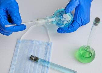 Fototapeta premium Scientist holding glass rod and flask at laboratory, closeup. Solution chemistry. Antivirus solution