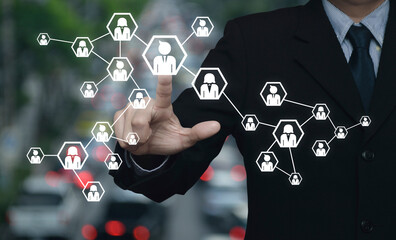Businessman pressing network icon over blur of rush hour with cars and road in city, Business communication concept