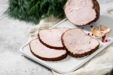 Meatloaf with herbs on a white ceramic serving Board on a light gray table. Baked meat