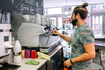Young waiter preparing the coffee machine in a cafeteria