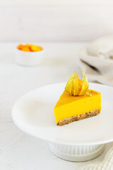 Slice of homemade pumpkin pie with physalis on a white plate. Sugar, lactose, gluten free.