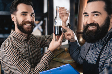 Two happy brewers welded bottle of dark beer.