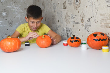 child hand paints and draws a pumpkin at halloween holiday close-up