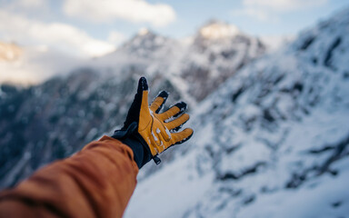 Hand winter sport glove on snow, ice and rock in the background. Snow and ice, blue sky. Winter...