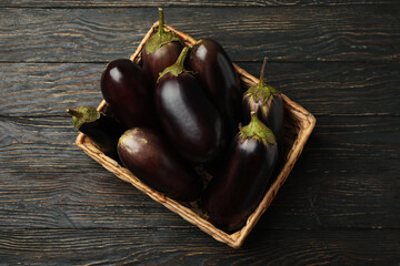 Basket with fresh eggplants on wooden background
