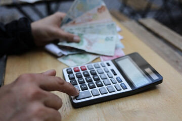 man doing financial transactions with calculator holding money in hand.