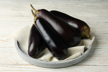 Tray with fresh eggplant on white wooden background