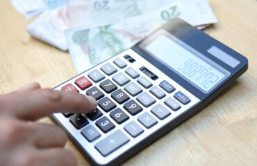 man doing financial transactions with calculator holding money in hand.