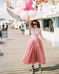 Happy girl with balloons in pink prom dresses at amusement park. Teenagers in pink evening dresses on vacation. Birthday party idea. © Love-Pics