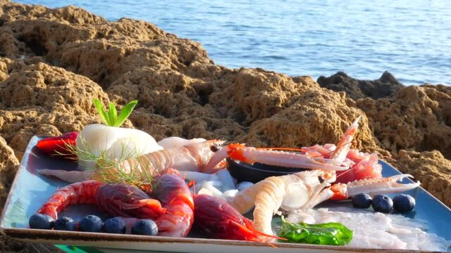 presentazione di piatto di crostacei e pesce crudo sugli scogli in riva al mare