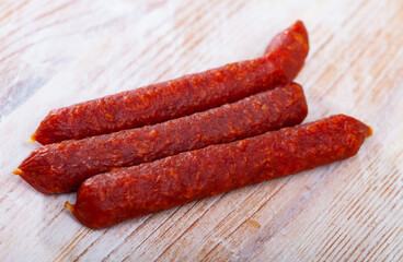 Popular thin smoked spicy Tyrolean sausages with chili peppers on wooden table..