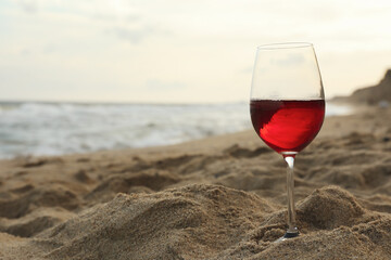 Glass of red wine on sandy sea beach