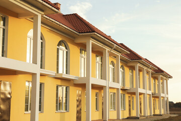 Beautiful new yellow townhouses with red - brown roof