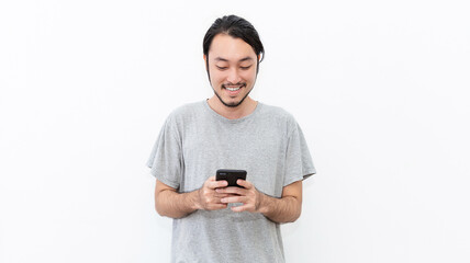 Portrait of happy young nerd asian man typing sms on smart phone isolated on white background. Technology communication with friends family work concept