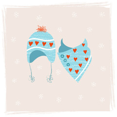 Hat with ties with red pompom and knitted scarf made of warm yarn. Set of warm knitted clothing for the cold season. Winter accessories in scandinavian style in soft blue colors and red hearts. 