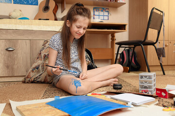 girl draws at home, artistic creation, makes creative artwork from paper, paints and brushes