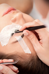 Young caucasian woman receiving eyelash extensions procedure in beauty salon